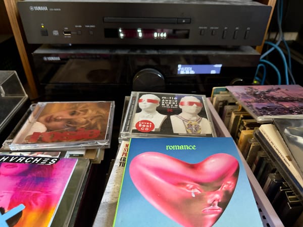 A pile of CDs sitting in front of a CD player.